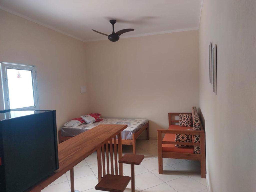Cette chambre comprend un lit, une table et une télévision. dans l'établissement Chalés Praia São Lourenço, à Bertioga