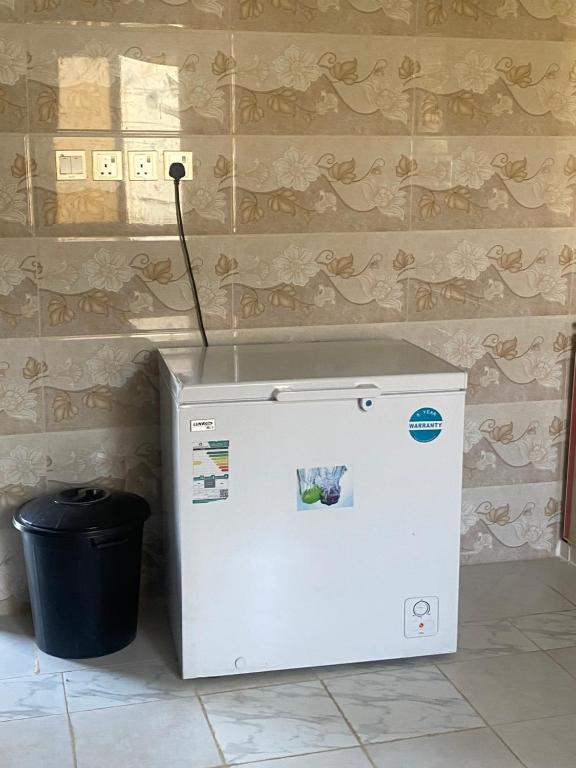 a white refrigerator with a wand next to a trash can at استراحة الشروق in Al ‘Uqūl