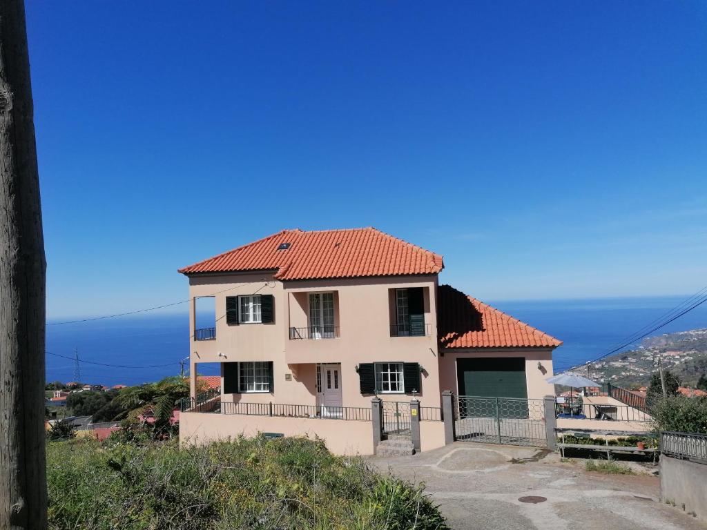 a house on a hill with the ocean in the background at Abrigo do Monte in Ribeira Brava