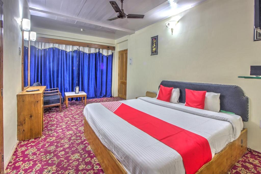 a bedroom with a large bed with blue curtains at Hotel Shishamaati in Kulu