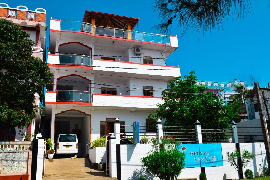 un edificio blanco con un coche aparcado delante de él en Orr's Hill Sea Side en Trincomalee