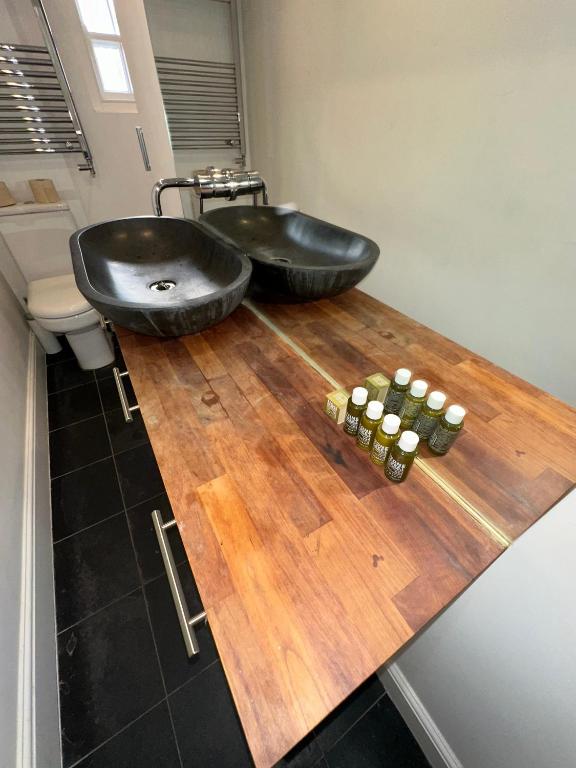 a bathroom with two black sinks and candles on a wooden counter at King’s Cross 2 bedroom apartment in London