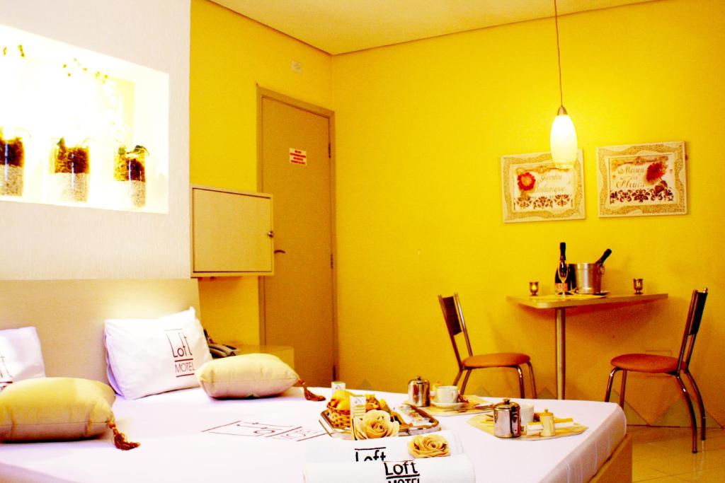 um quarto com duas camas e uma mesa e cadeiras em Loft Motel em Santos