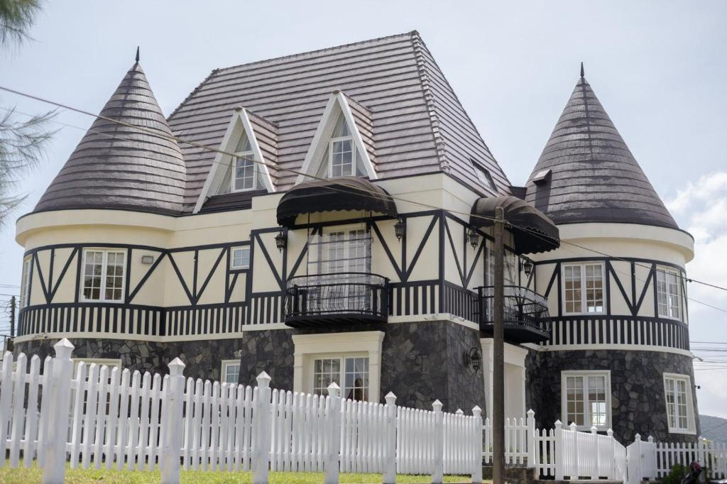 a black and white house with a white fence at Maple Castle in Nuwara Eliya