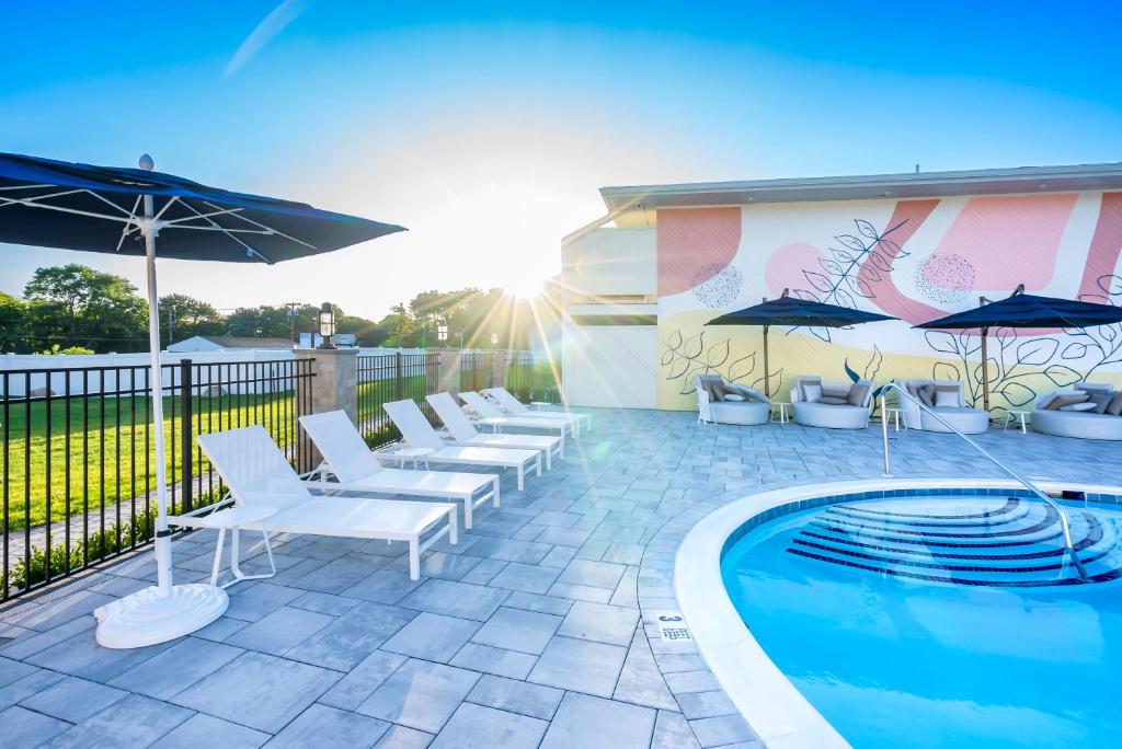 a pool with chairs and umbrellas next to a building at The Bentley Hotel Southampton in Southampton