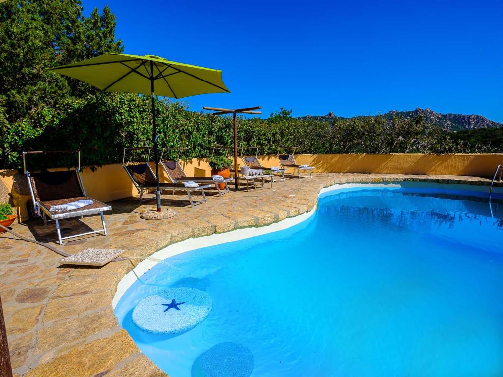 a swimming pool with chairs and an umbrella at Sardinia Family Villas - Villa Nina with private pool in Abbiadori