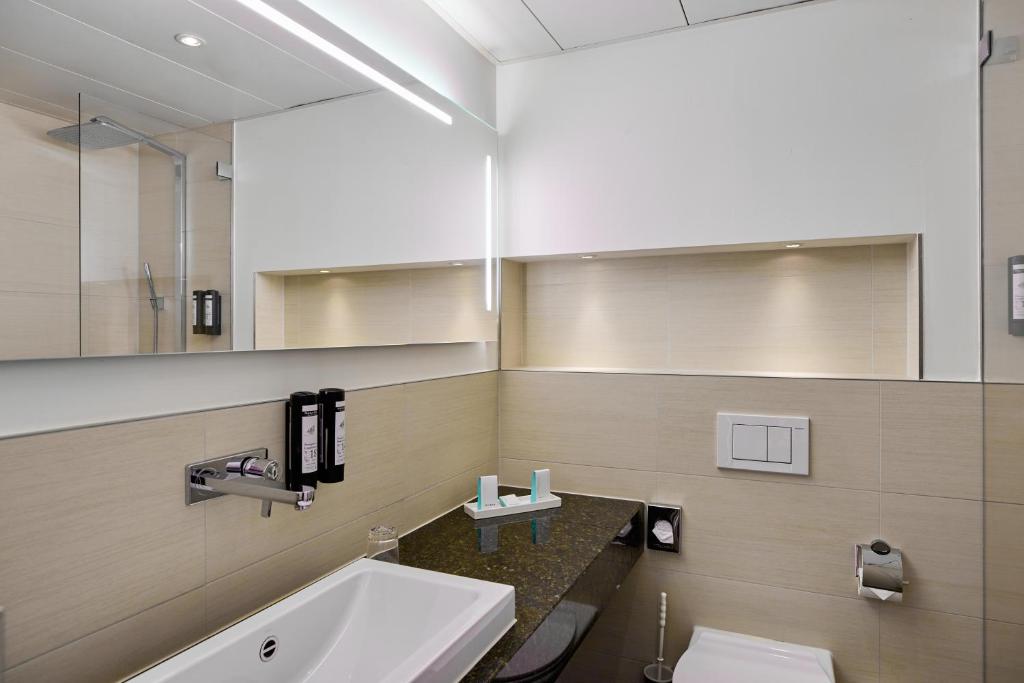 a bathroom with a sink and a toilet and a mirror at Hotel St.Gotthard in Zürich