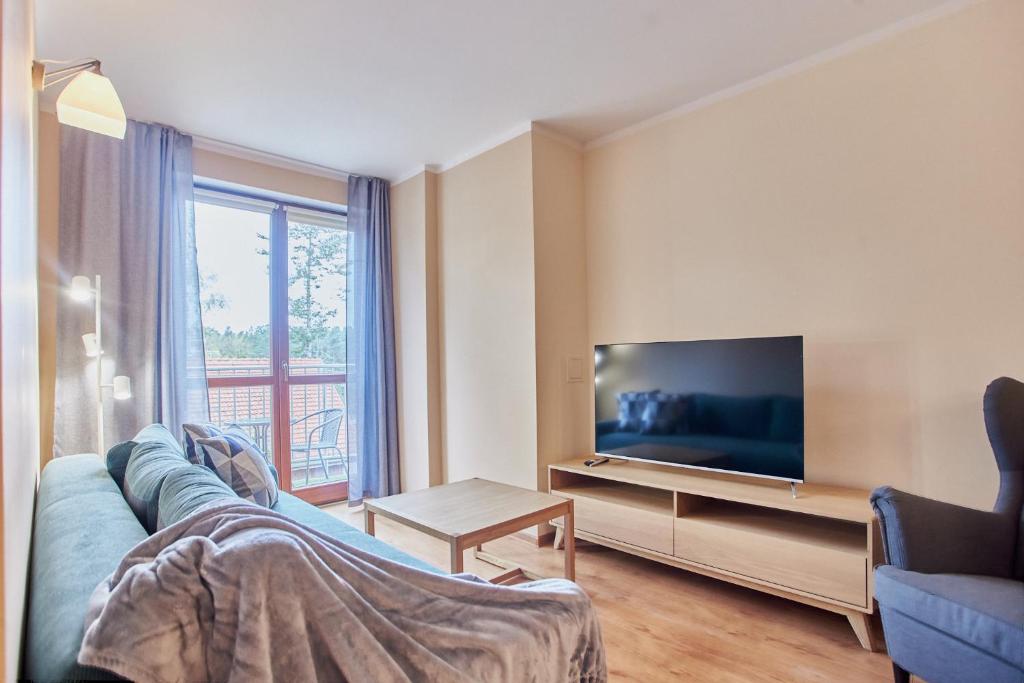 un salon avec un canapé bleu et une télévision dans l'établissement Apartamenty Świnoujście - Rezydencja Żeromskiego, à Świnoujście