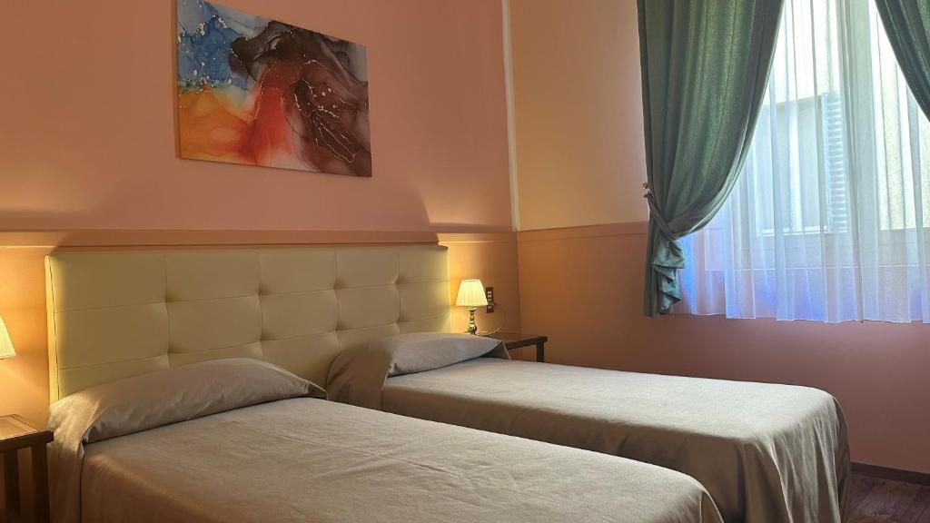 a hotel room with two beds and a window at Hotel Roma in Bologna