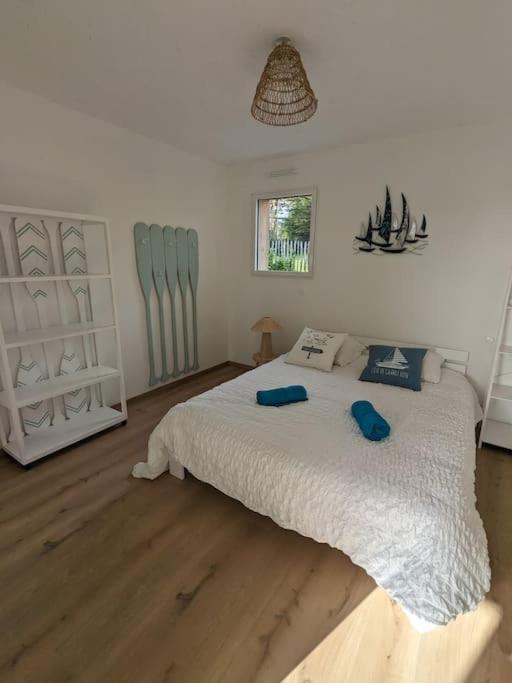 Un dormitorio con una gran cama blanca con almohadas azules. en La Bernique blanche de Perros vue mer 4 personnes, en Perros-Guirec