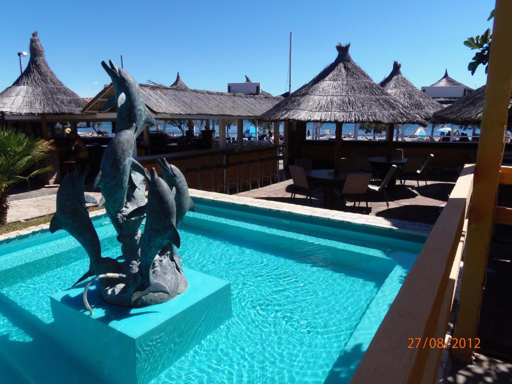 Tribunia Beach Hotel في تريبونج: تمثال عصفورين على صخرة بجوار حمام سباحة