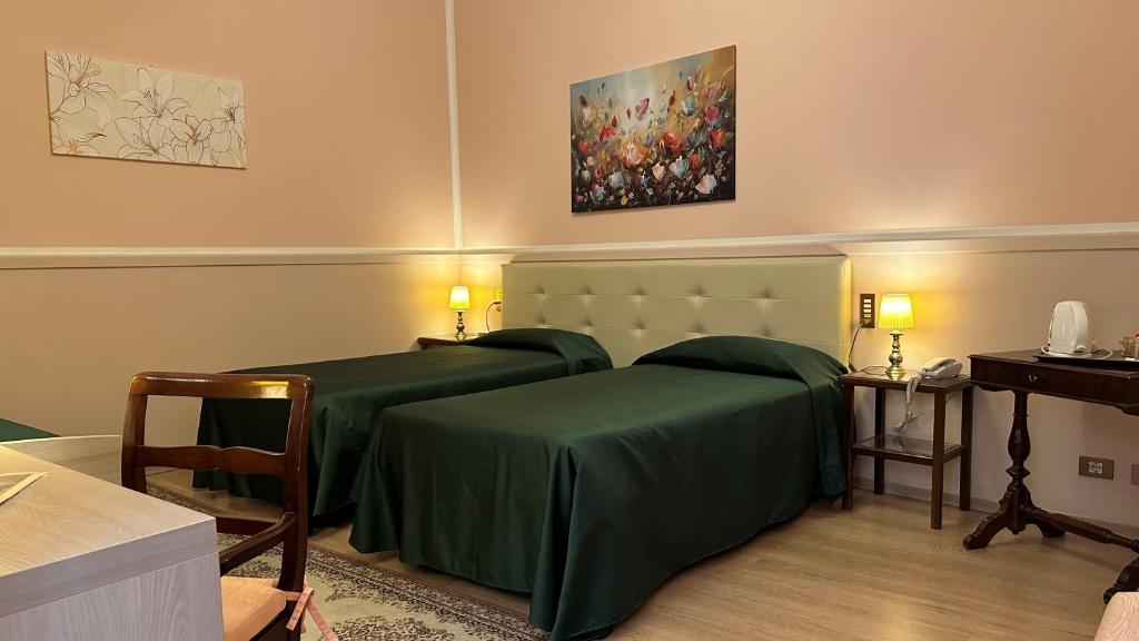 a bedroom with two green beds and a painting at Hotel Roma in Bologna