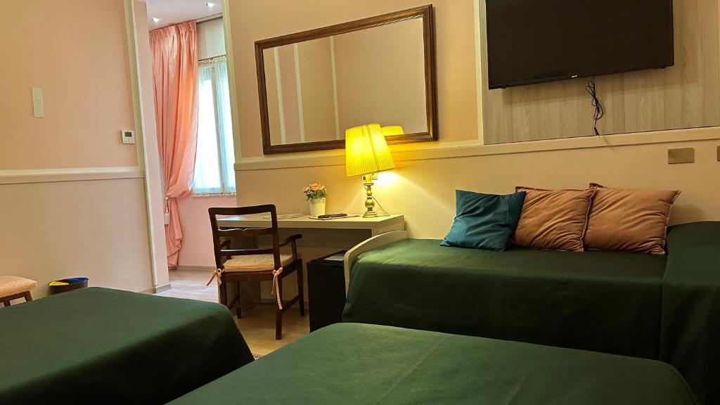 a hotel room with two green beds and a desk at Hotel Roma in Bologna