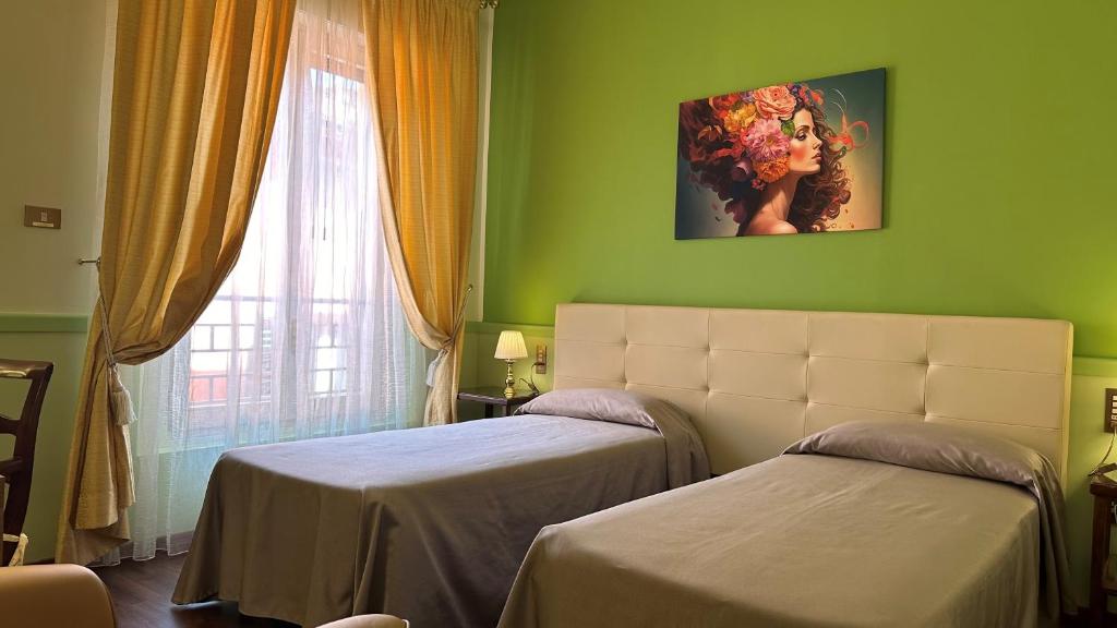 a green room with two beds and a window at Hotel Roma in Bologna