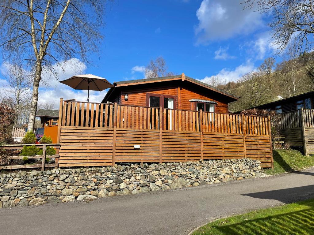 a wooden house with a fence and an umbrella at Lavender Lodge in Windermere