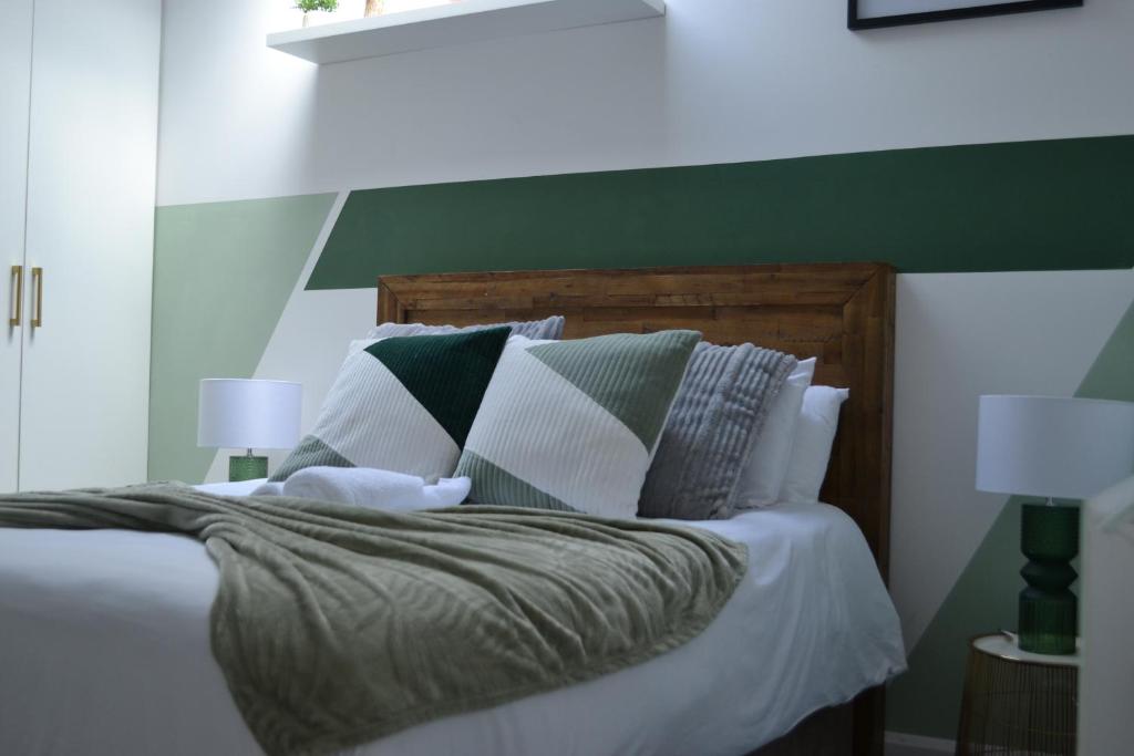 een slaapkamer met een bed met groene en witte kussens bij Stylish 1 Bed Apartment 5, free parking 5 mins to CityCentre in Birmingham