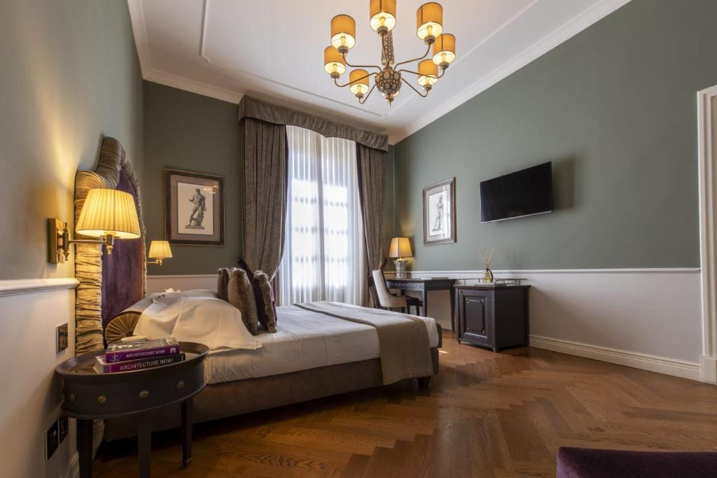 1 dormitorio con cama, escritorio y lámpara de araña en Palazzo Roselli Cecconi, en Florencia