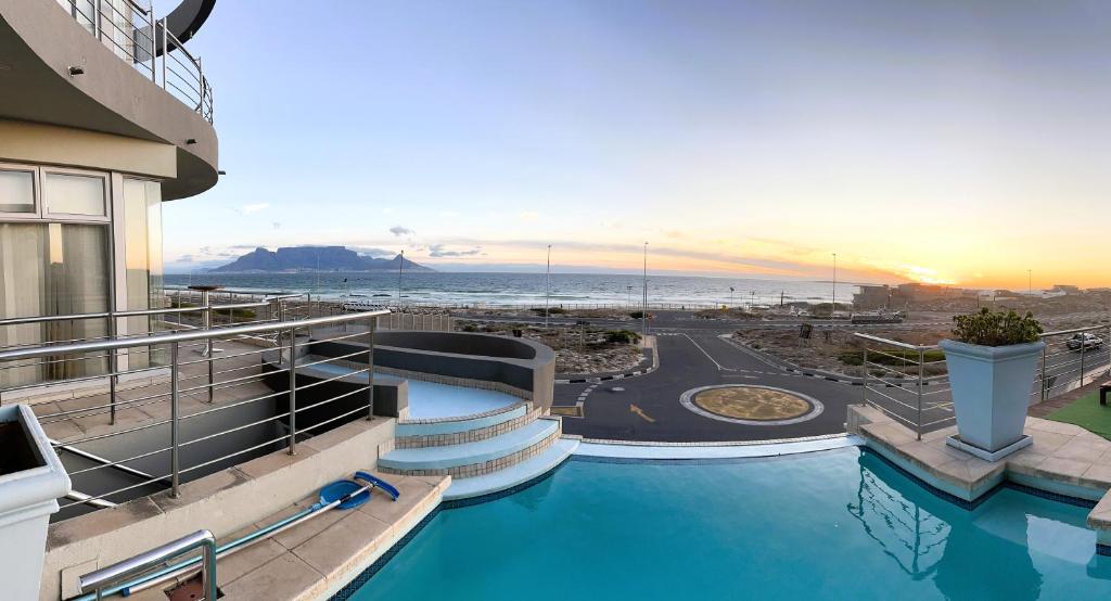 a resort with a pool with a view of the beach at Oceansnest Guest House in Bloubergstrand