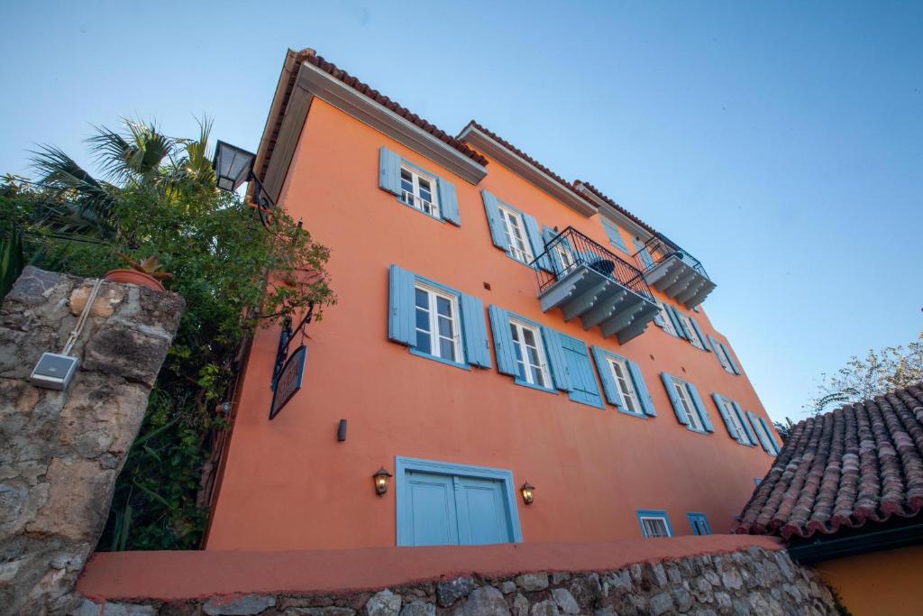 an orange building with blue windows and a palm tree at Byron Traditional Hotel in Nafplio