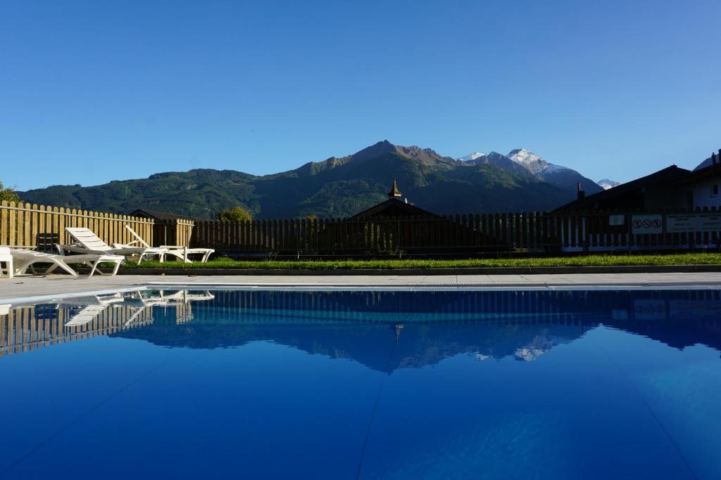 a swimming pool with a chair and mountains in the background at Panorama-Apartment Fürth in Aufhausen
