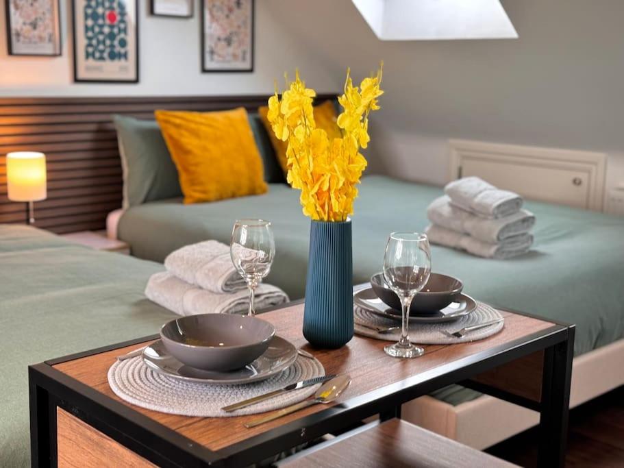 une table avec deux assiettes et un vase avec des fleurs jaunes dans l'établissement Superb Studio in Wembley 30min to Central London, à Londres