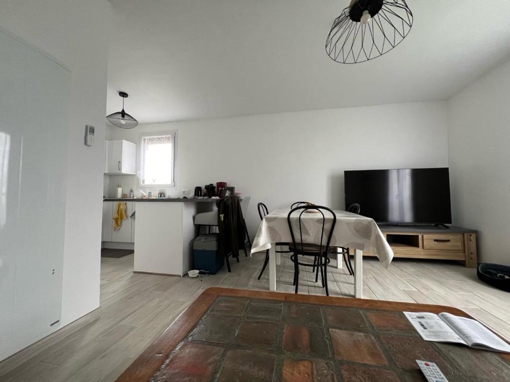 a white living room with a table and a television at Appartement Brise Marine in Grandcamp-Maisy