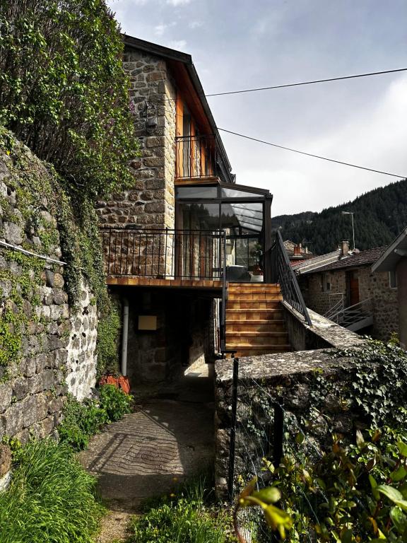 une maison en pierre avec un escalier et un balcon. dans l'établissement L’Hacienda, maison de caractère, à Saint-Martin-de-Valamas