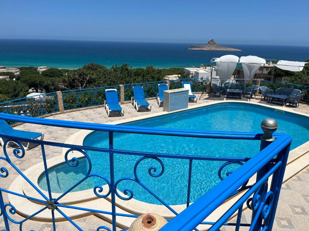 einen Pool mit Stühlen und das Meer im Hintergrund in der Unterkunft Mille ou une nuit in Tunis