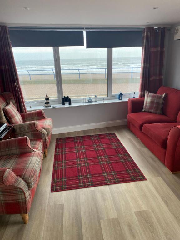 uma sala de estar com dois sofás e vista para a praia em Beach Cottage em Berwick-Upon-Tweed