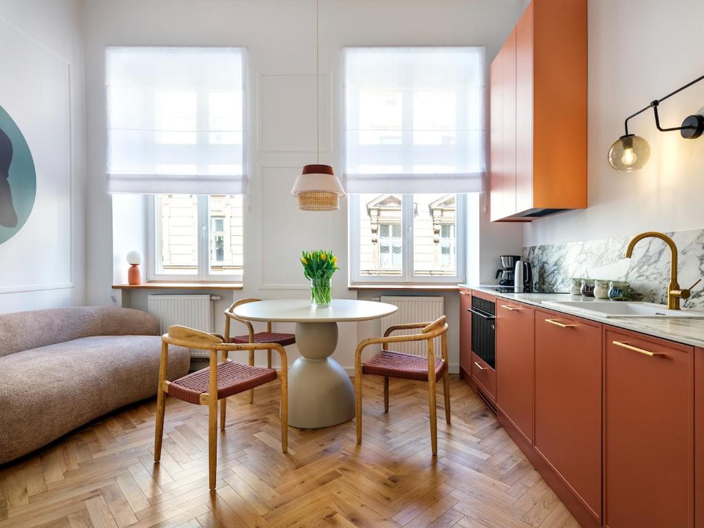 een keuken met een tafel en stoelen in een kamer bij Tyzenhauz Apartments Siemiradzkiego Street in Krakau