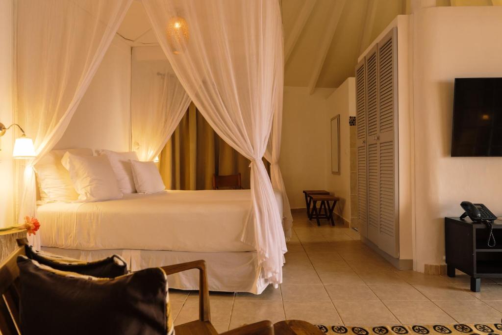 Principe的住宿－普林西比波烏波烏酒店，一间卧室配有一张带窗帘的床和电视。