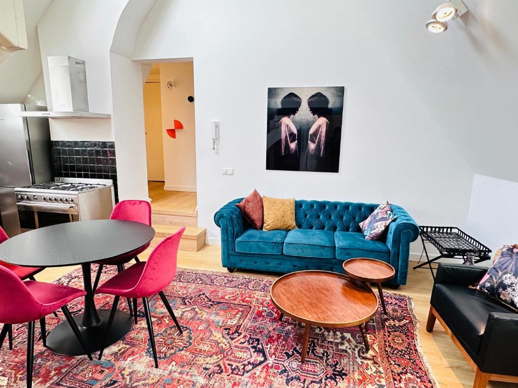 ein Wohnzimmer mit einem blauen Sofa und rosa Stühlen in der Unterkunft Gilly's Gallery in Breda
