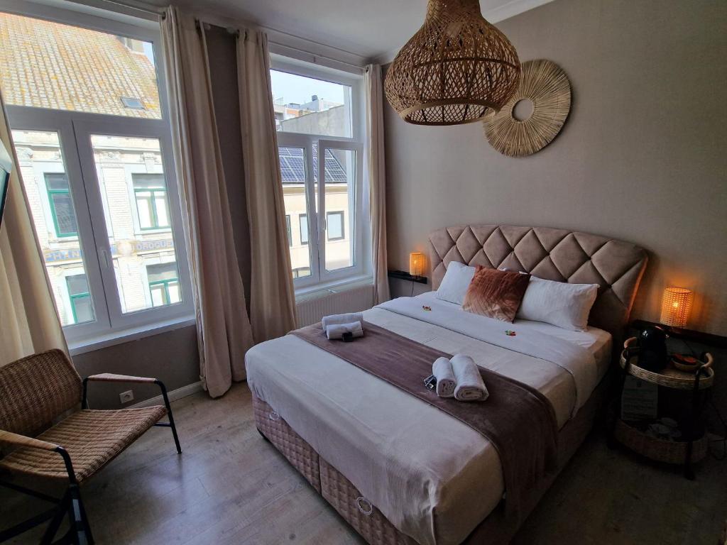 a bedroom with a bed and a chair and windows at Nonne Blanche in Ostend