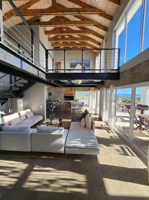 a living room with white couches and a balcony at Mustique-Beachfront bliss in St. Helena Bay