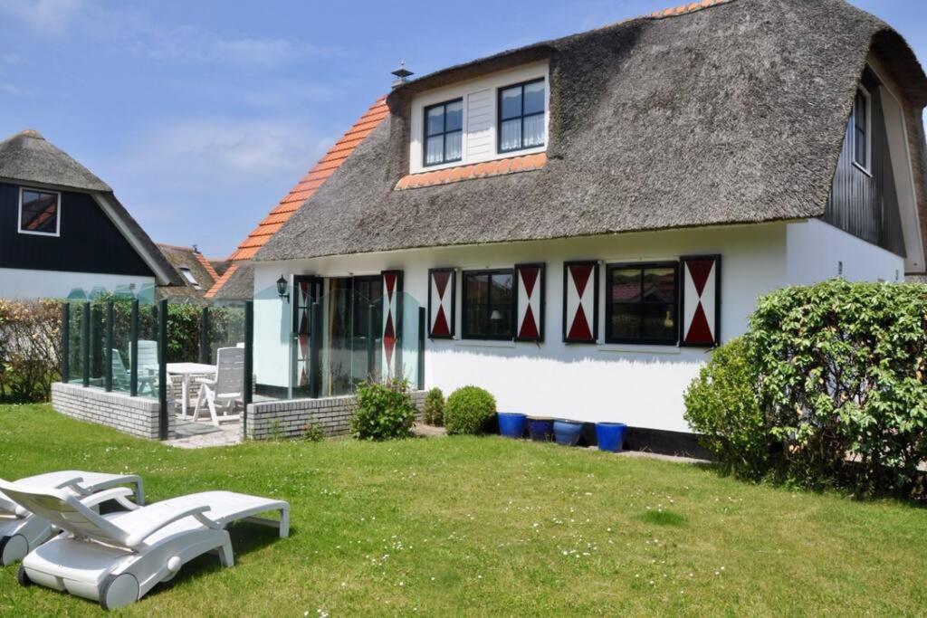 a house with a thatched roof and a yard at Buitenplaats 144 in Callantsoog
