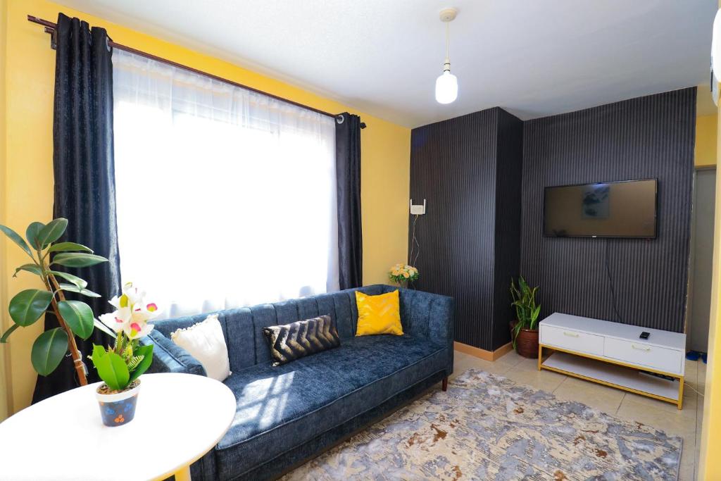 uma sala de estar com um sofá azul e uma televisão em The Perfect New Nest em Nairobi