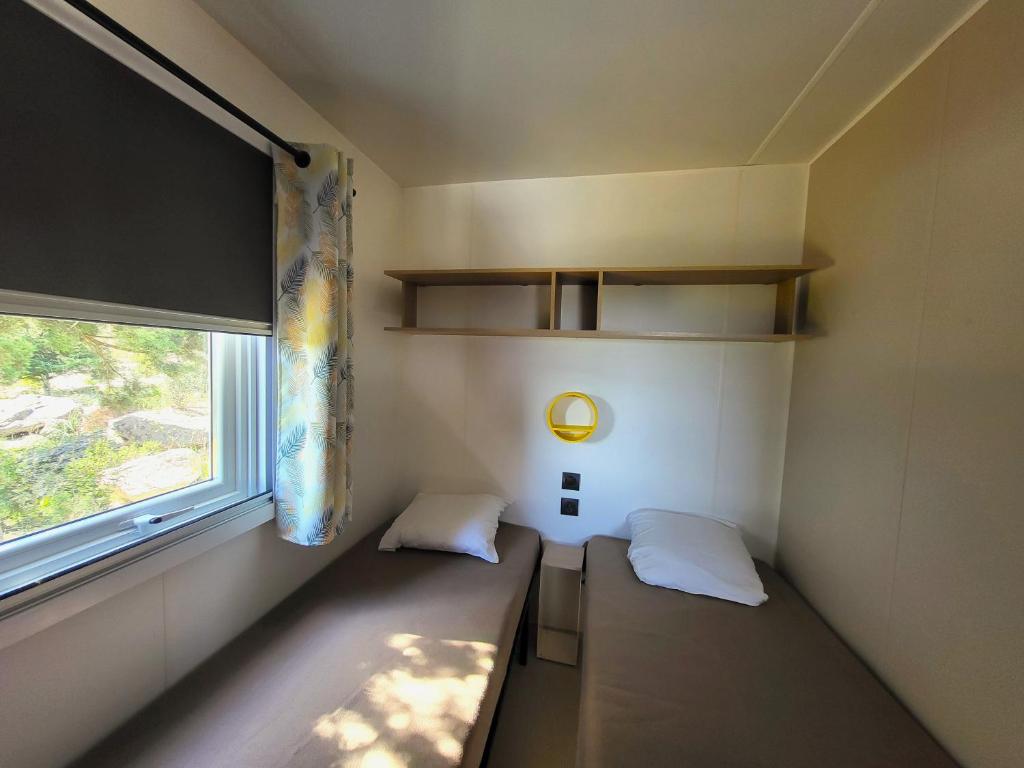 Habitación pequeña con 2 camas y ventana en Camping Rondinara, en Bonifacio
