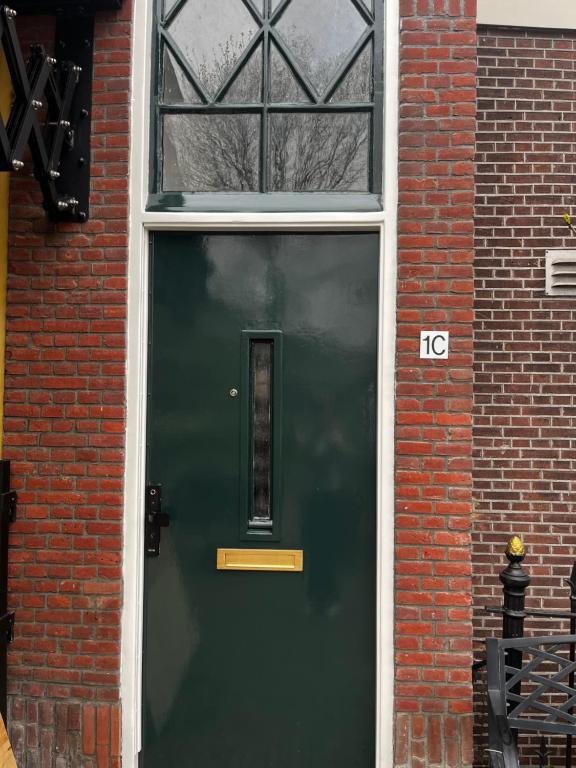 a green door in a brick building with a window at Stays by ADM in Leiden