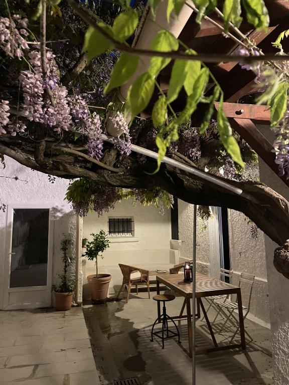 une terrasse avec une table, des chaises et des fleurs violettes dans l'établissement Maison de ville Logement entier, à Avignon