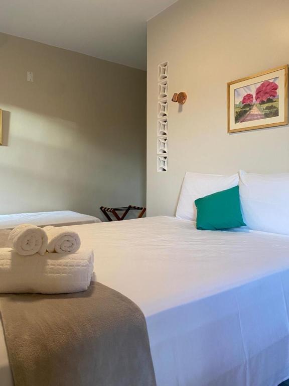 a bedroom with a large white bed with towels on it at Pousada Mãe Natureza in Pirenópolis