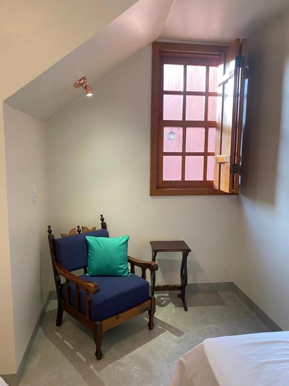 a room with a blue chair and a window at Pousada Mãe Natureza in Pirenópolis