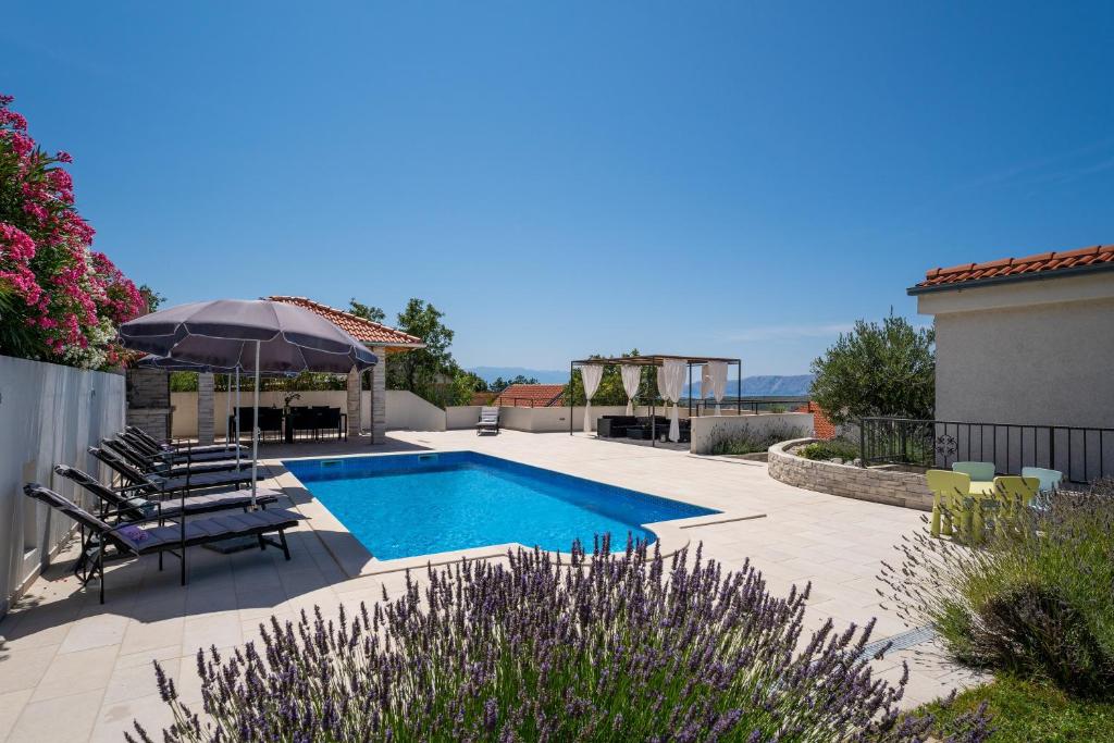 una piscina in un cortile con sedie e ombrellone di Pool House Edita - Happy Rentals a Bribir