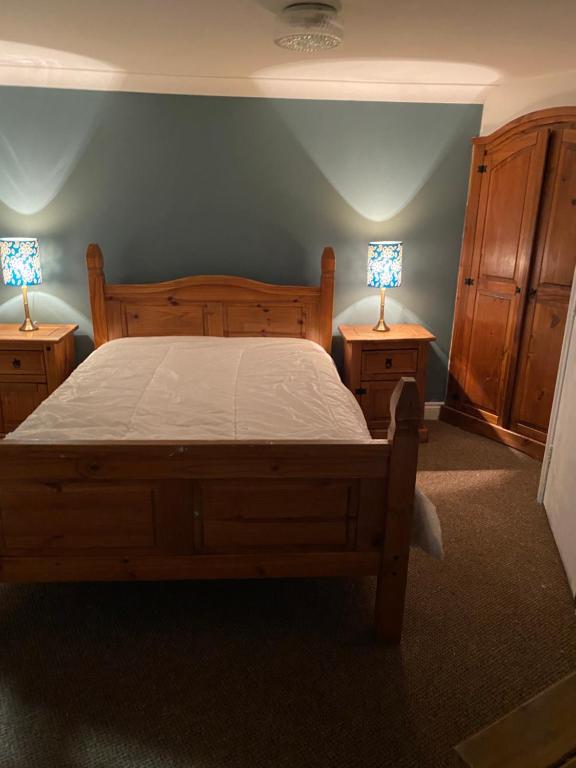 a bedroom with a wooden bed and two night stands with lamps at The Granary Bar & Grill in Long Sutton