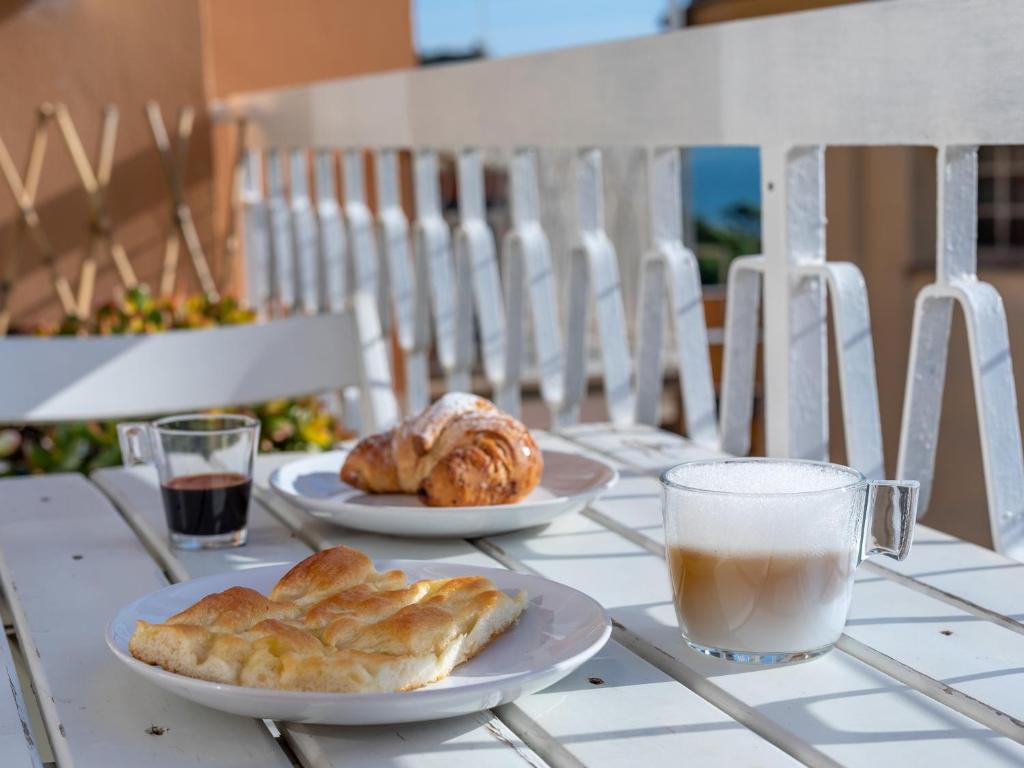 a table with two plates of pastries and a glass of milk at Moneglia Beach Downtown in Moneglia