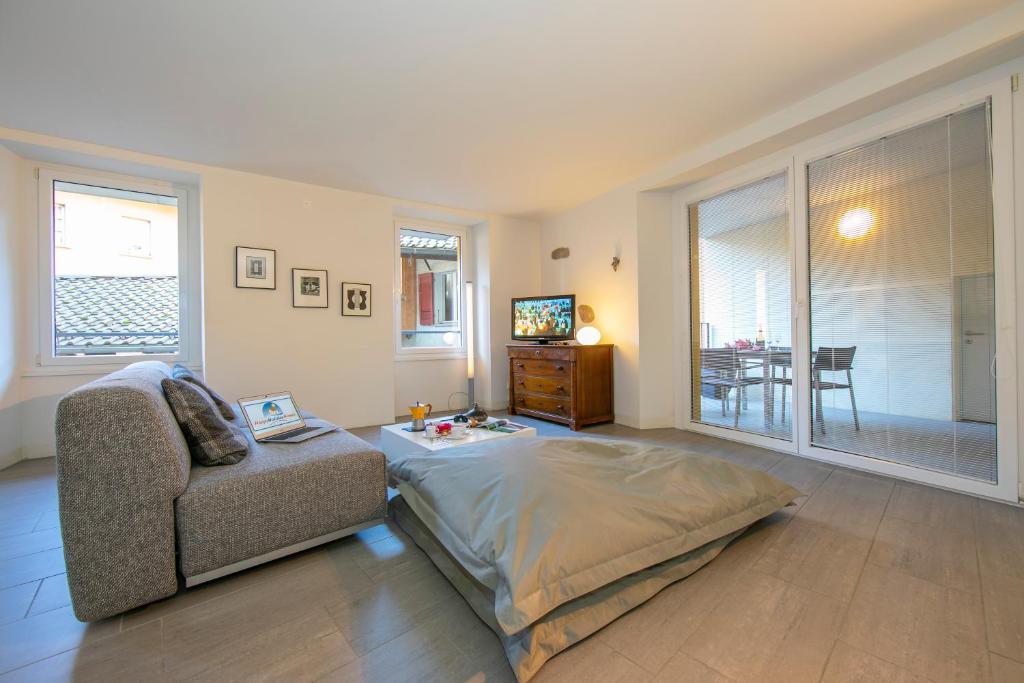 a bedroom with a bed and a couch and a chair at Antico Municipio - Happy Rentals in Ponte Tresa