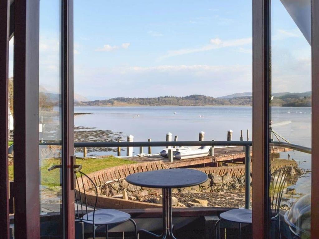 a view of the water from a balcony with a table and chairs at Dundonald Landing Lochside Studio in Oban
