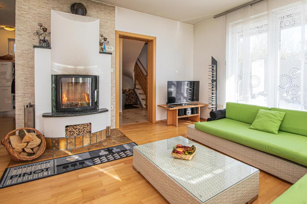 sala de estar con sofá verde y chimenea en Sunny Weekend Sauna House - Happy Rentals en Preserje