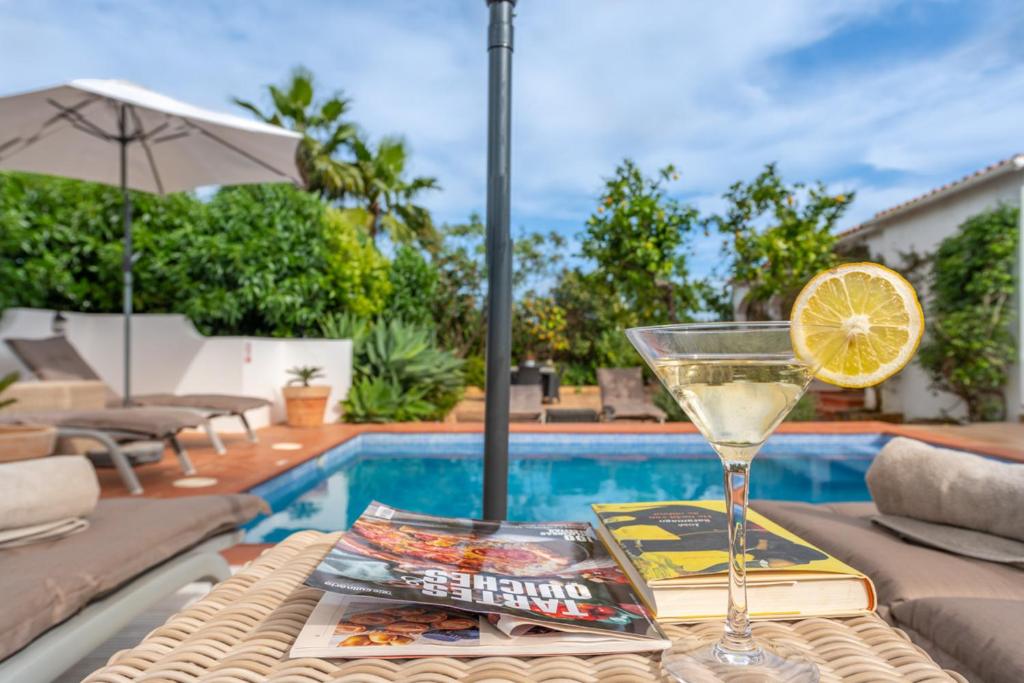 a drink on a table next to a swimming pool at Quinta das Piteiras Turismo Rural in Silves