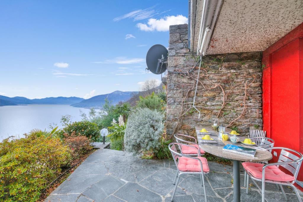 een tafel en stoelen op een patio met uitzicht op het water bij Casa Brighella - Happy.Rentals in Brissago