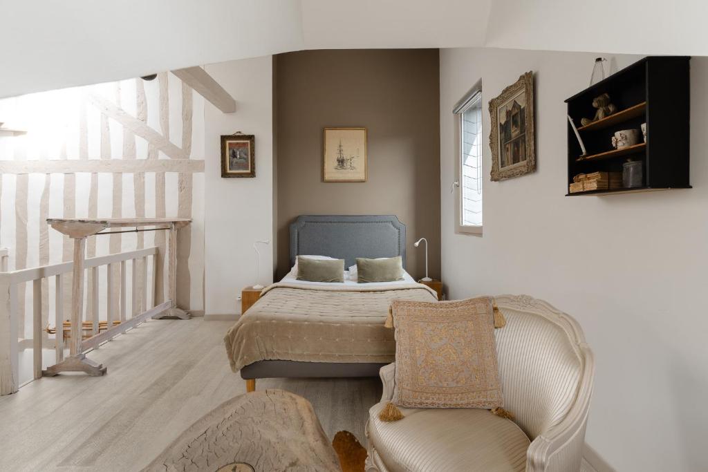 a bedroom with a bed and a chair at Studio et appartements Sainte Catherine in Honfleur